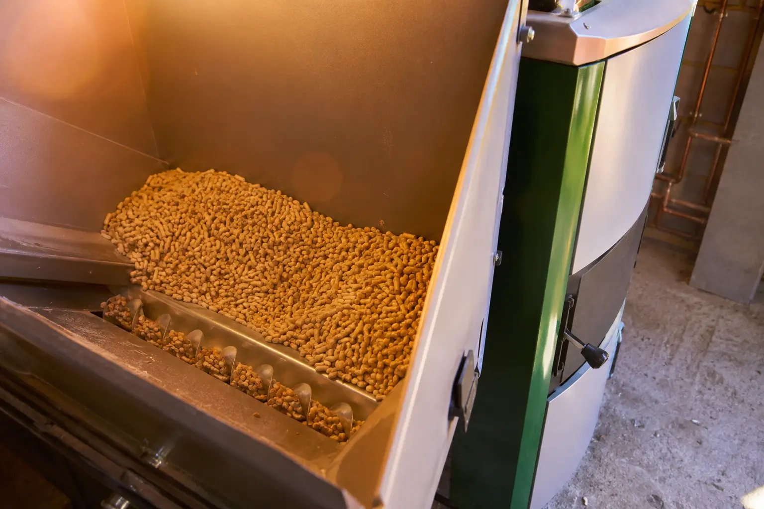 Wood pellets being poured into the hopper of a biomass boiler