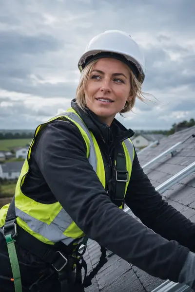 Solar panel installer fitting roof-mounted PV panels on an Irish home