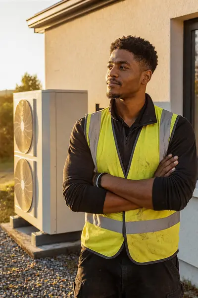 An installer in a hi-vis vest beside a twin-fan heat pump outdoor unit, typical of the work SEAI registered installers in Mayo carry out